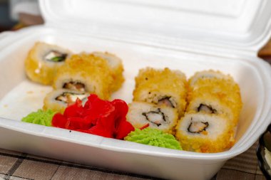 Peynirli hamurda pişirilmiş yılan balığı ve karides ile suşi ve yiyecek kutusunda zencefil. Yüksek kalite fotoğraf