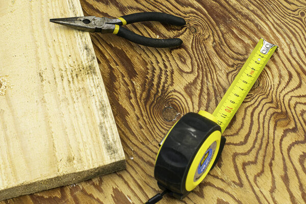 measuring tape measure board and pliers on the workbench. High quality photo