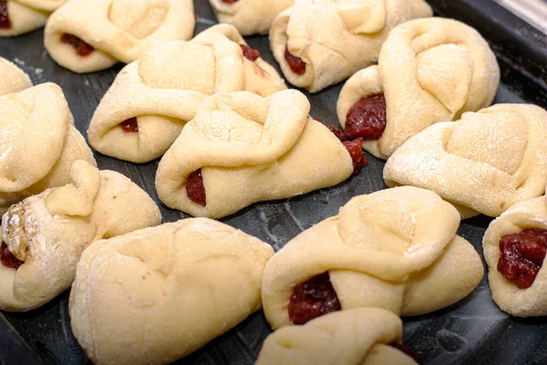 homemade cakes with jam on a baking sheet prepared for baking. High quality photo