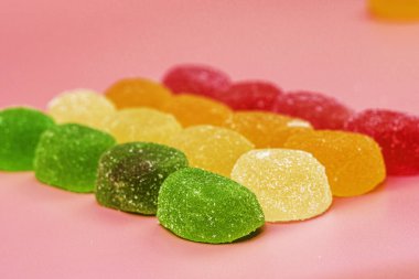Renkli marmelat şekerlemeleri pembe arka planda serili