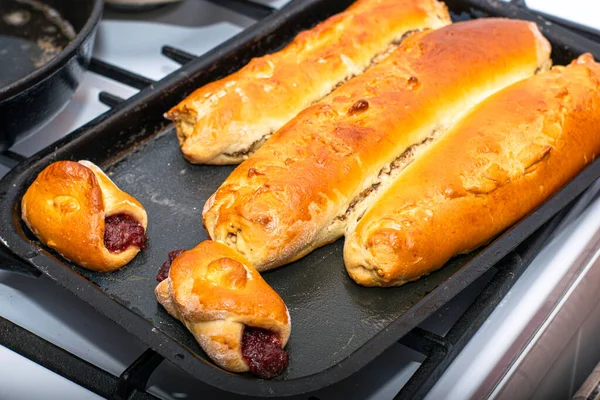 Pasteles recién horneados y rollos dorados en una bandeja para hornear — Foto de Stock