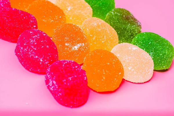 Bunte Marmelade Bonbons in Reihen von Farbe auf einem rosa Hintergrund ausgelegt — Stockfoto