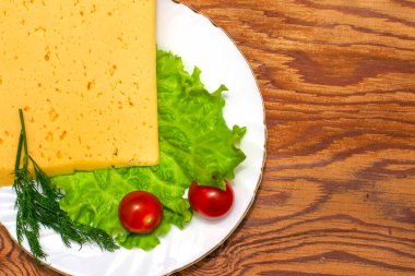 Büyük bir parça peynirli marul, kirazlı domates ve otlar tahta bir masa fotokopi alanında beyaz bir tabakta. Yüksek kalite fotoğraf