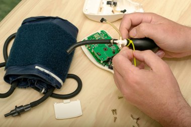 Usta elektronik tonometreyi tamir eder plastik bir klemple plastik ampulü tamir eder. Yüksek kalite fotoğraf