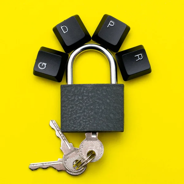 closed iron padlock with keys on a yellow background on the lock lever the keys of the computer keyboard are lined with the abbreviation GDPR the concept of personal data protection. High quality photo