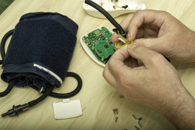 Usta elektronik tonometreyi tamir eder plastik bir klemple plastik ampulü tamir eder. Yüksek kalite fotoğraf