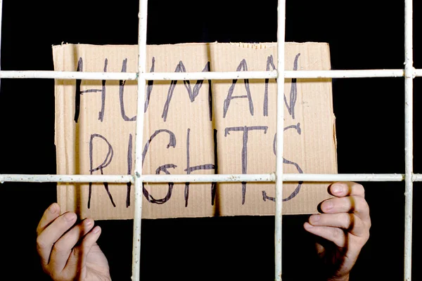 the concept of human rights freedom of speech hands hold a cardboard sign with the inscription human rights behind the iron prison bars. High quality photo