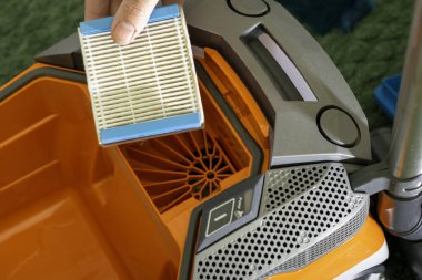 Adam hava filtresini elektrik süpürgesinden çıkarıp yerine yenisini koyuyor. Yüksek kalite fotoğraf