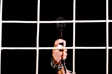 İnsan hakları kavramı ifade özgürlüğü demir zincirli bir el demir parmaklıkların arkasında bir mikrofon tutar.