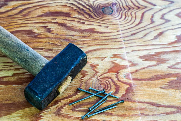 Un gran martillo de hierro y clavos en un espacio de copia de superficie de madera — Foto de Stock