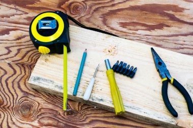 Bant pense kalem tornavidaları ve marangozların tezgahında bir tahta.