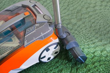 Yeşil bir halının arka planında elektrikli süpürge yıkamak.