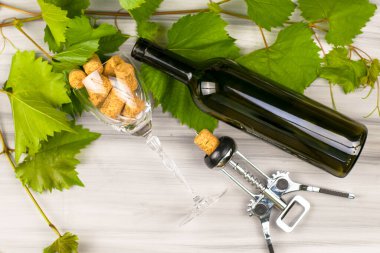 glass goblet with wine stoppers wine bottle corkscrew with a twisted wine stopper and grape branches on a painted wooden background. High quality photo
