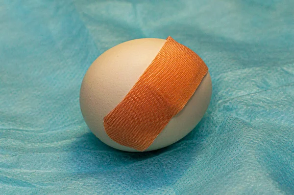 chicken egg with a medical patch pasted on a medical napkin concept vaccination medicine