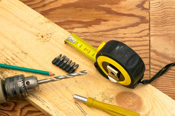 Misurazione del trapano a nastro con un cacciaviti a matita su un banco da lavoro in legno — Foto Stock