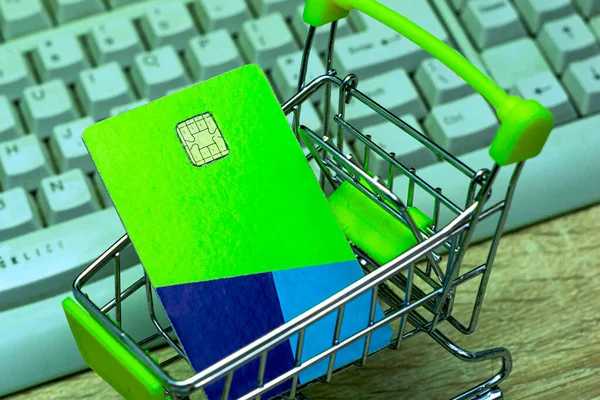 Bilgisayarın arka planında kredi kartı olan bir alışveriş arabası internet bankacılığı konsepti. Yüksek kalite fotoğraf