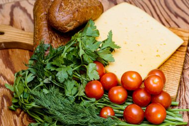 Bir parça peynir, kirazlı domates ve çavdar ekmeği masanın üzerindeki tahta kesme tahtasının üzerinde. Yüksek kalite fotoğraf