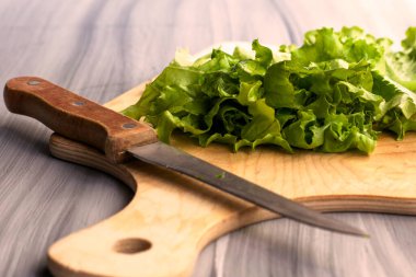 Marul yaprakları kesim tahtasının üzerinde, masada bir bıçağın yanında. Yüksek kalite fotoğraf