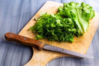 Marul yaprakları kesim tahtasının üzerinde, masada bir bıçağın yanında. Yüksek kalite fotoğraf