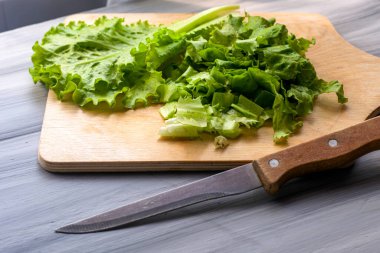 Marul yaprakları kesim tahtasının üzerinde, masada bir bıçağın yanında. Yüksek kalite fotoğraf