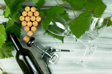 Şarap mantarları üzüm fırçası dalları, şarap tirbuşonu, şarap şişesi ve ahşap arka planda iki cam bardak şeklinde serilmiştir. Yüksek kalite fotoğraf