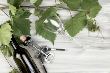 grape branches a wine corkscrew a bottle of wine and a glass glass on a painted wooden background. High quality photo