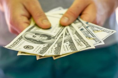 Bir adam elinde bir yığın yüz dolarlık banknot tutar. Yüksek kalite fotoğraf