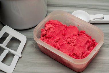 Masanın üzerinde, dondurma kaşığı ve dondurma makinesinin yanında duran plastik bir kapta ev yapımı vişneli dondurma. Yüksek kalite fotoğraf
