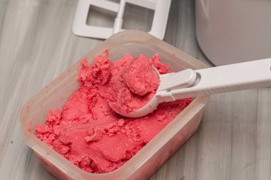 Masadaki plastik bir kapta, dondurma kaşığı ve dondurma makinesiyle ev yapımı vişneli dondurma. Yüksek kalite fotoğraf