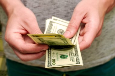 Bir adam 100 dolarlık banknotlardan oluşan bir tomar parayı sayar. Yüksek kalite fotoğraf