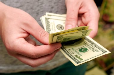 Bir adam 100 dolarlık banknotlardan oluşan bir tomar parayı sayar. Yüksek kalite fotoğraf