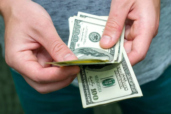 Bir adam 100 dolarlık banknotlardan oluşan bir tomar parayı sayar. Yüksek kalite fotoğraf