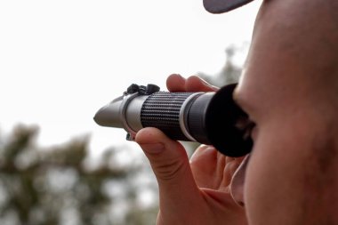 Şarap üreticisi, üzüm suyunun şeker içeriğini belirlemek için kırılma ölçere bakar. Yüksek kalite fotoğraf