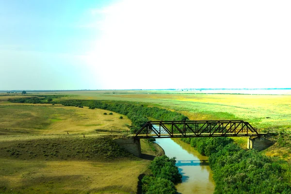 在乡间路上的草原上一座横跨河流的旧铁桥 一幅无人驾驶飞机的照片 高质量的照片 — 图库照片