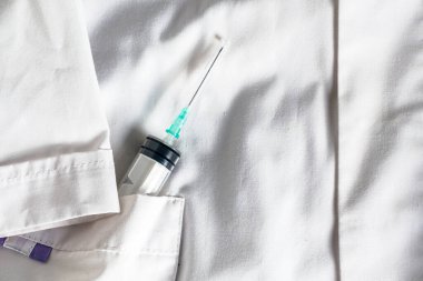 Beyaz bir tıp önlüğünün yan cebinde iğne olan bir şırınga. Yüksek kalite fotoğraf