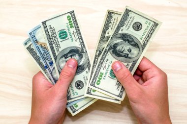 Masada oturan bir adam yüz dolarlık banknotları sayar. Yüksek kalite fotoğraf