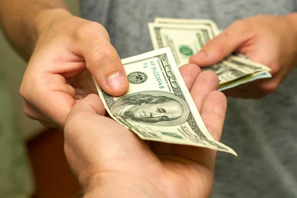 Bir kişi, bir diğerinin yanından yüz dolarlık banknotları sayarak geçer. Yüksek kalite fotoğraf