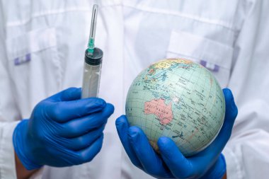Beyaz önlüklü ve koruyucu eldivenli bir doktor şırınga ve globus aşısı taşıyor. Yüksek kalite fotoğraf