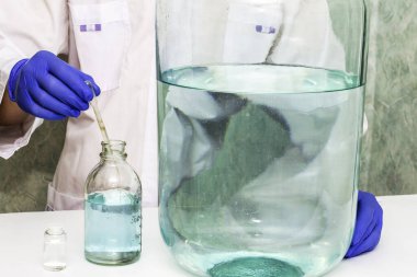 Laboratuvardaki bir laboratuvar asistanı diğer boyutlardaki damarların yanında pipetle bir baloncuktan sıvı çeker. Yüksek kalite fotoğraf