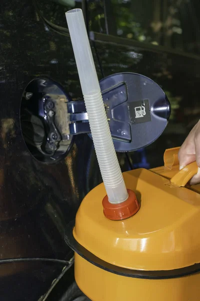 Mężczyzna Trzyma Pomarańczowy Kanister Benzyną Ręku Obok Samochodu Wężem Odpływowym — Zdjęcie stockowe