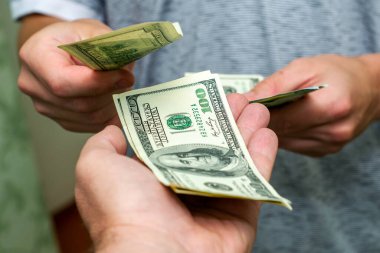 Bir kişi, bir diğerinin yanından yüz dolarlık banknotları sayarak geçer. Yüksek kalite fotoğraf