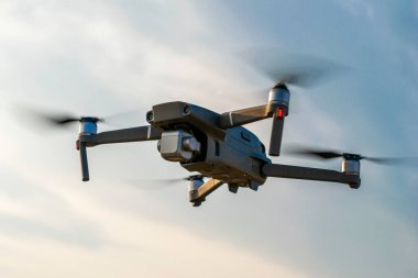 Bir kuadrokopter dron bulutlarla gökyüzünün arka planına doğru uçuyor. Yüksek kalite fotoğraf