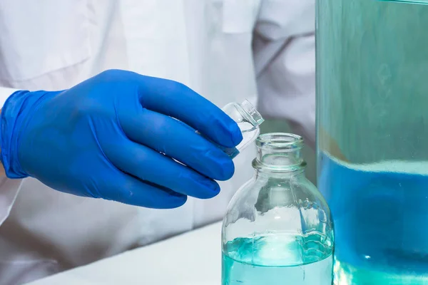a doctor in the laboratory pours liquid from one bottle into another close-up. High quality photo