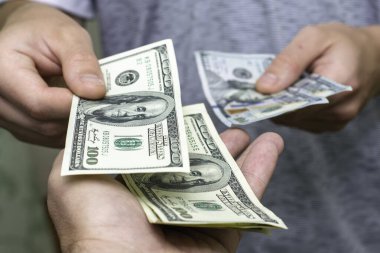 Bir kişi, bir diğerinin yanından yüz dolarlık banknotları sayarak geçer. Yüksek kalite fotoğraf