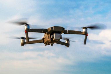 Bir kuadrokopter dron bulutlarla gökyüzünün arka planına doğru uçuyor. Yüksek kalite fotoğraf