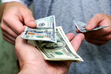 Bir kişi, bir diğerinin yanından yüz dolarlık banknotları sayarak geçer. Yüksek kalite fotoğraf