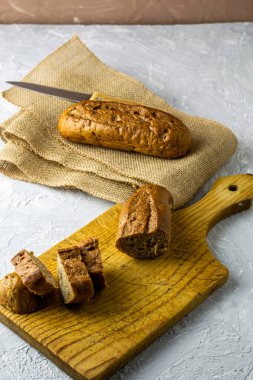 Kesme tahtasının üzerinde iki taze çavdar ekmeği ve bir çuval bezi. Bir tanesi kesilmiş. Yanında bir bıçak var. Yüksek kalite fotoğraf