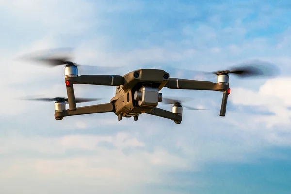 Bir kuadrokopter dron bulutlarla gökyüzünün arka planına doğru uçuyor. Yüksek kalite fotoğraf
