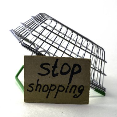 Makul tüketimi satın almayı reddetme kavramı, üzerinde yazıtların durduğu bir tabelanın yanındaki beyaz arka planda ters dönmüş bir alışveriş sepetidir. Yüksek kalite fotoğraf