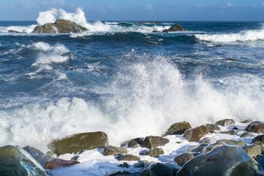 İspanya, Tenerife yakınlarındaki dalgalı Atlantik Okyanusu, sudaki kayalıklarda güçlü dalgalar kopuyor.